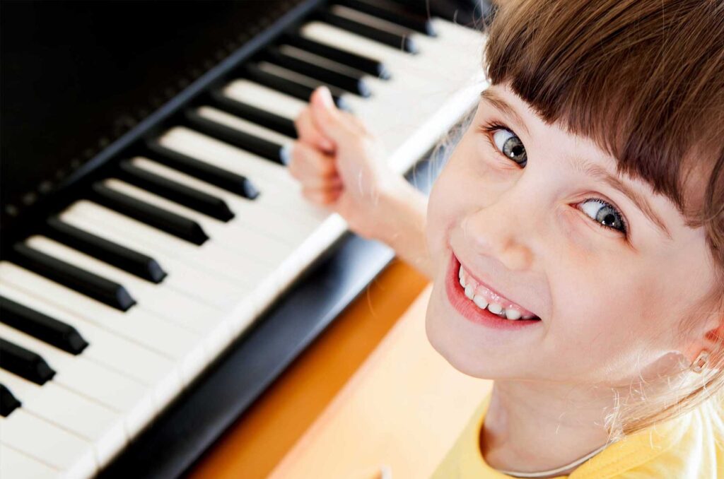 a girl smiling at the piano